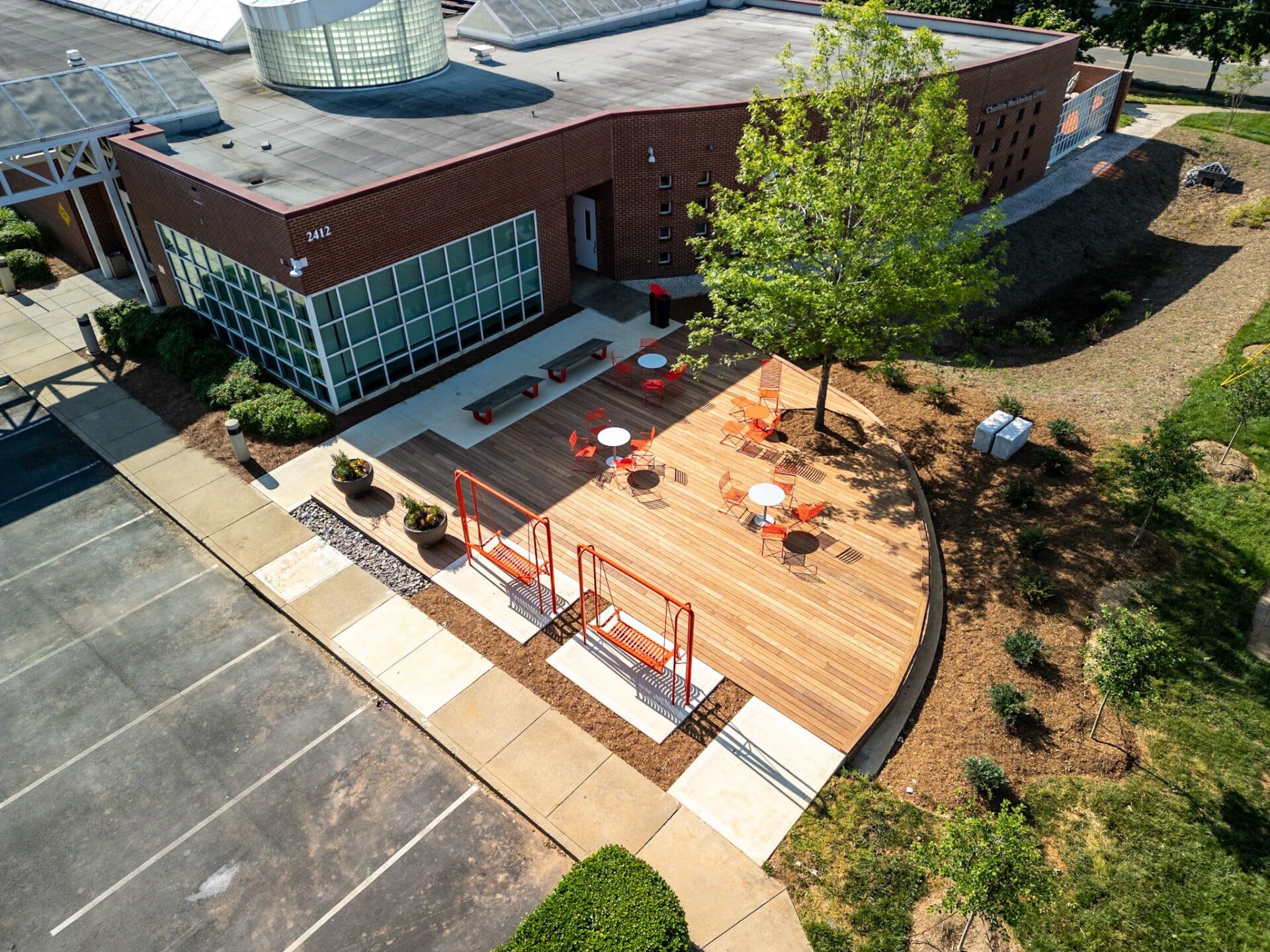 Expansive curved hardwood deck featuring modern orange seating and detailed landscaping, custom built by Carolina Decks in the Charlotte, NC area.