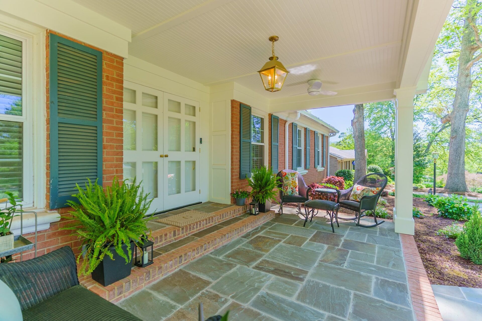 Covered porch with beadboard ceiling, flagstone patio, and brick steps, custom built by Carolina Decks in the Stonehaven neighborhood.