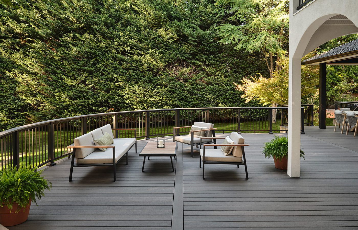 Sleek, dark grey curved composite deck with modern black metal railing and outdoor furniture, custom built by Carolina Decks in the Charlotte, NC area.