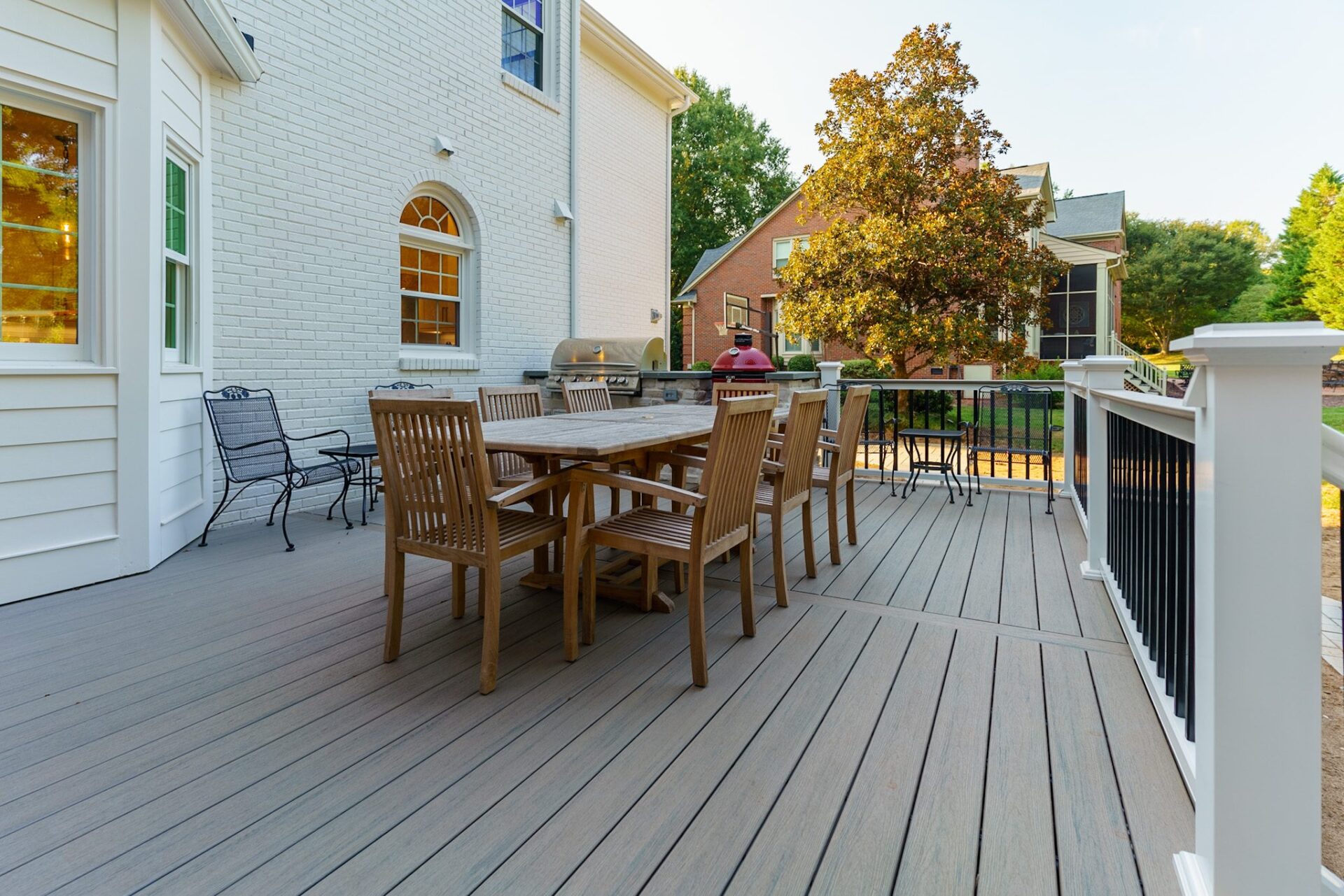Spacious gray composite deck with white railing, black balusters, and a built-in stone grill station, custom built by Carolina Decks in the Charlotte, NC area.