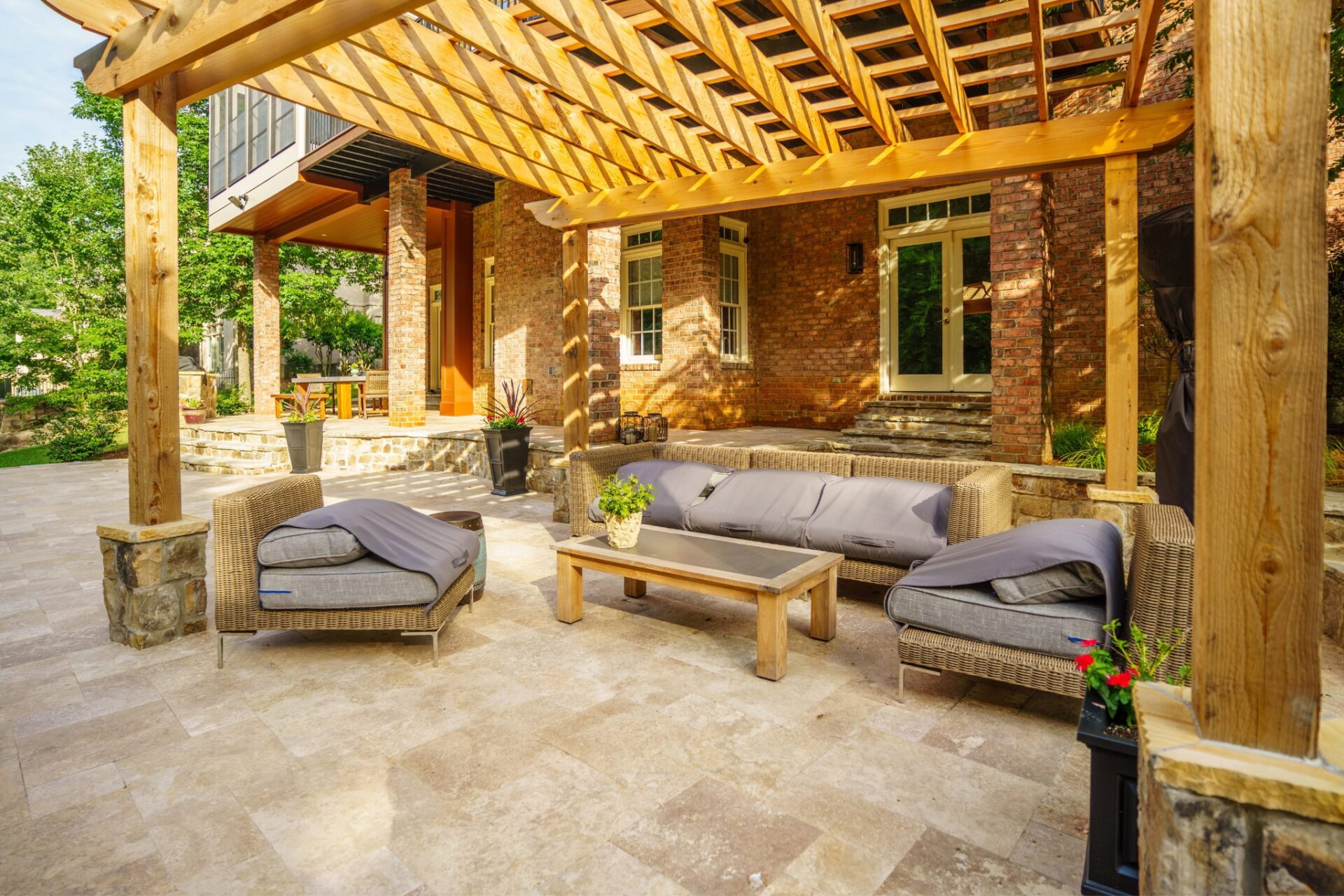 Expansive timber pergola shading a stone paver patio with comfortable outdoor living space, custom built by Carolina Decks in the Charlotte, NC area.