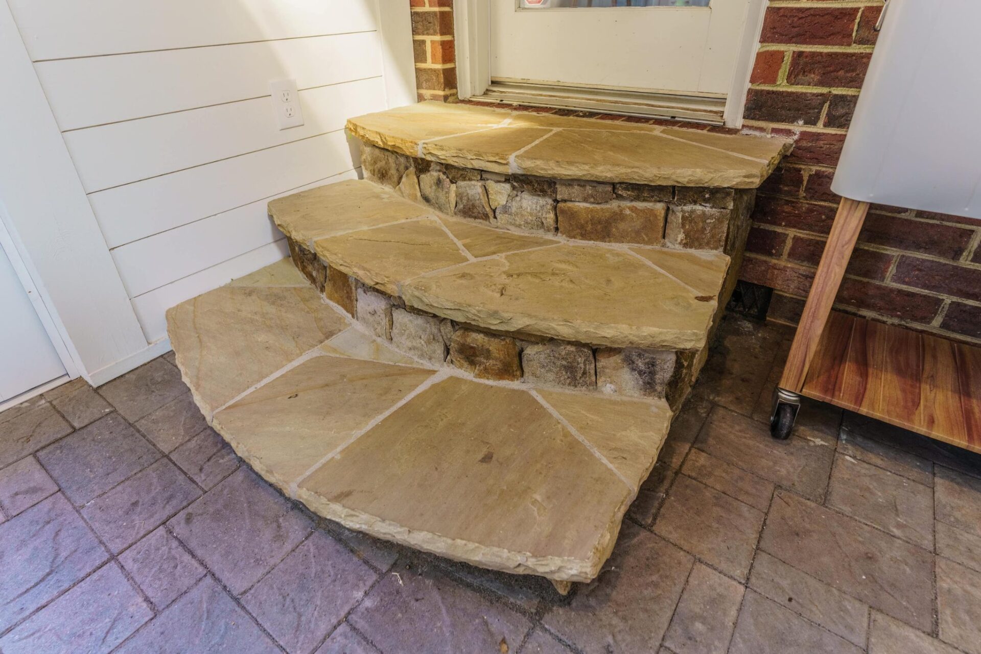 Curved flagstone steps with natural stone risers leading to a paver patio, custom built by Carolina Decks in the Charlotte, NC area.