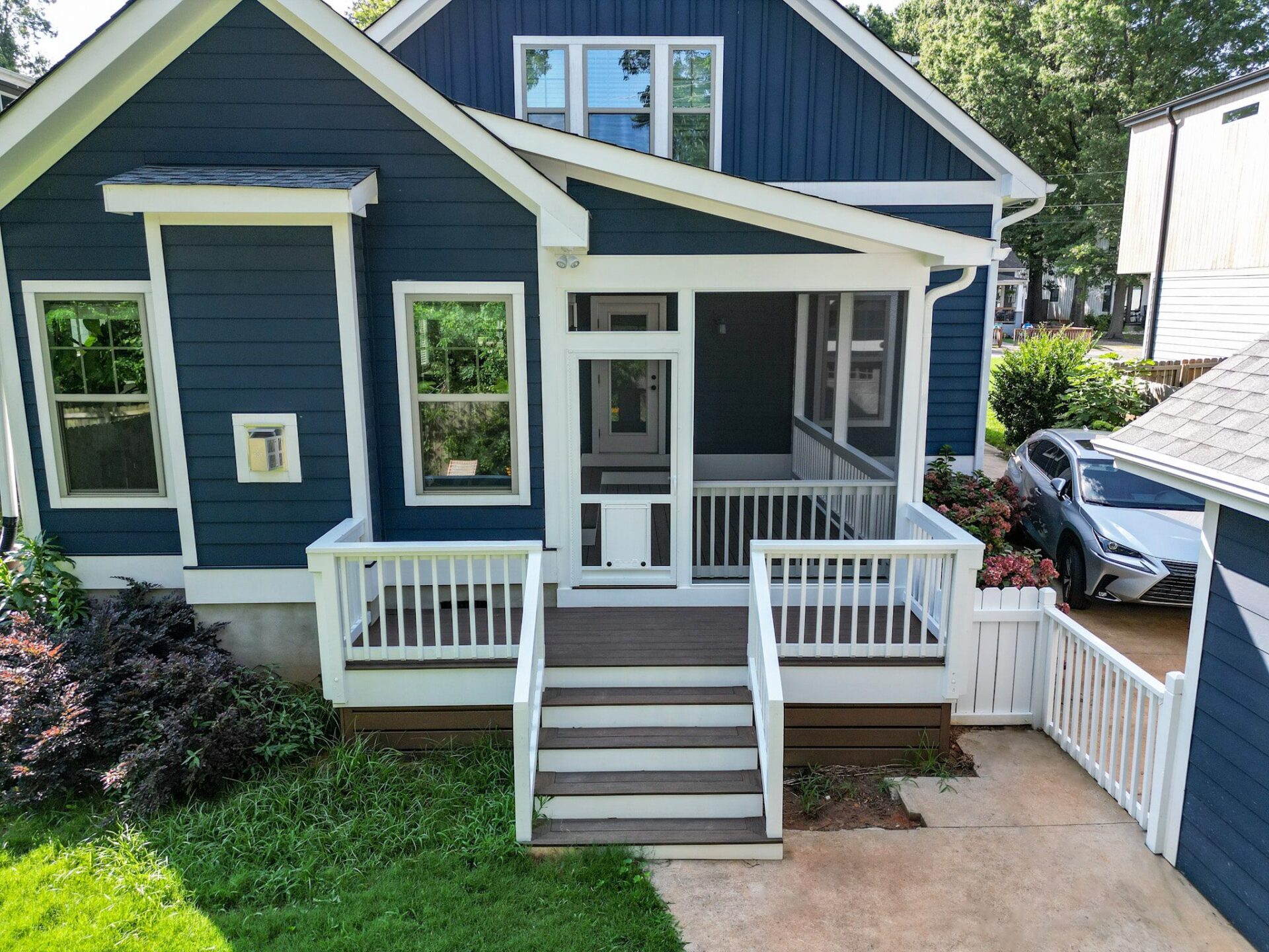 Dark blue house with white trim features a screened porch, composite deck, white railings, and steps, custom built by Carolina Decks in the the Center City area.