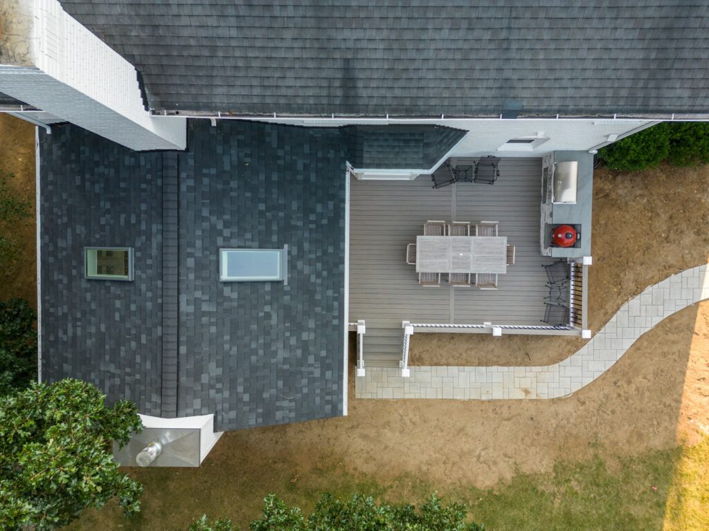 Premium composite deck with outdoor kitchen and winding paver path, custom built by Carolina Decks in the Charlotte, NC area.