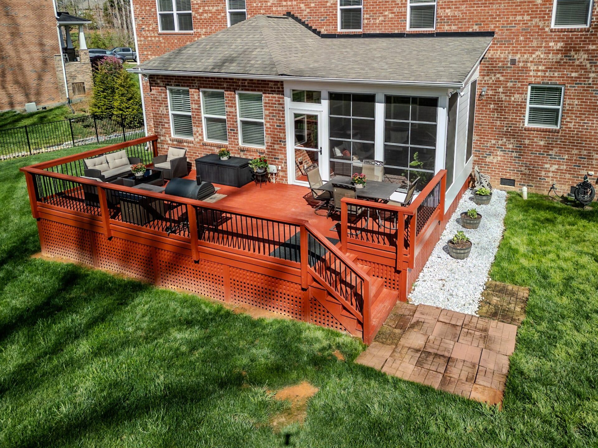 Red wood deck, black railings, screened porch, and paver path, custom built by Carolina Decks in Mint Hill