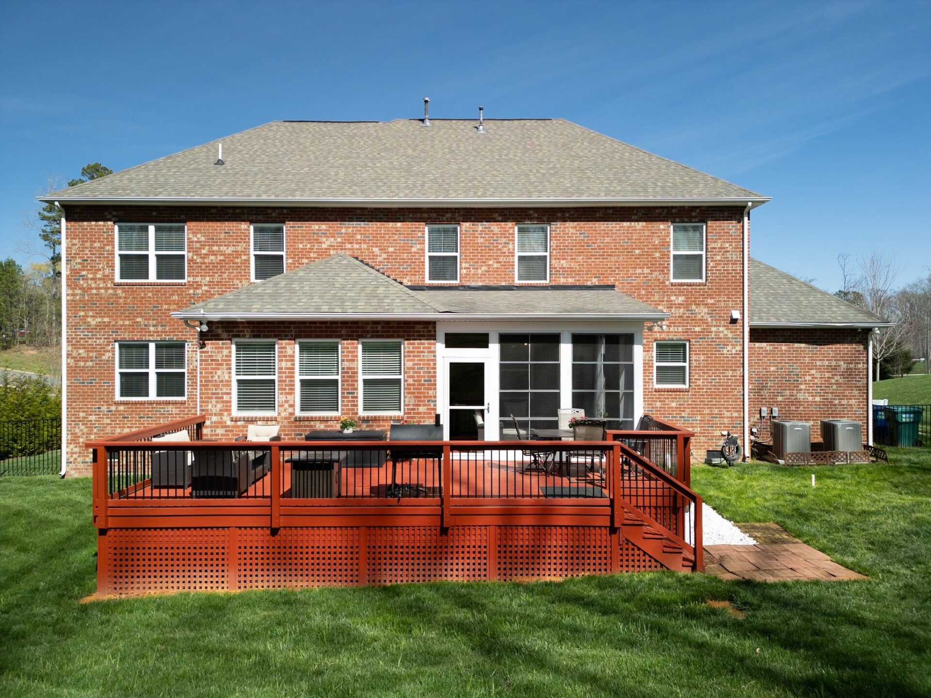 Red wood deck with black balusters and lattice, plus a screened porch, custom built by Carolina Decks in Mint Hill.