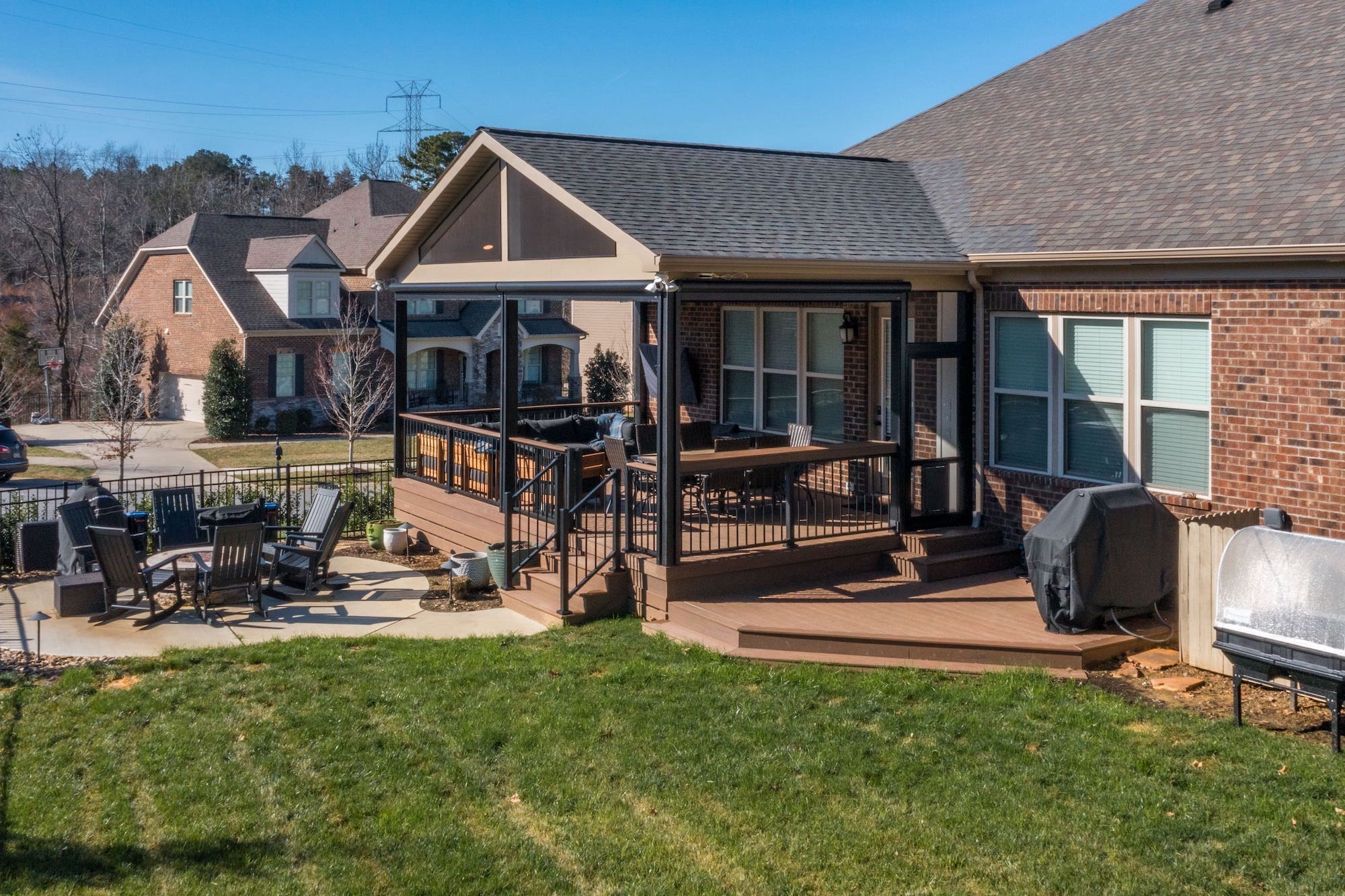 Multi-level composite deck with A-frame screened porch, black railings, and concrete patio, custom built by Carolina Decks in the Charlotte, NC area.