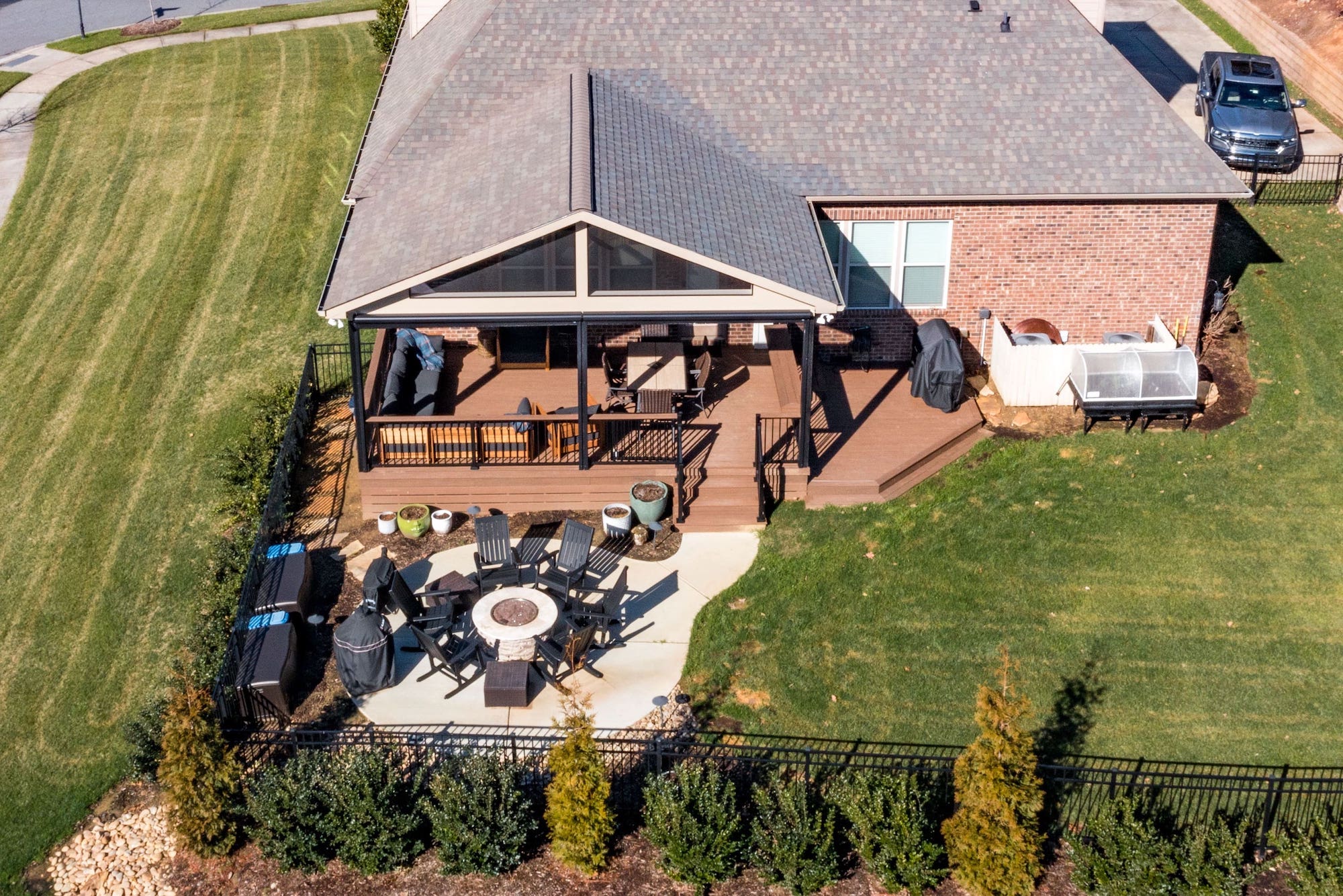 Spacious brown composite deck, covered porch, and concrete patio with fire pit, custom built by Carolina Decks in the Skybrooke area.