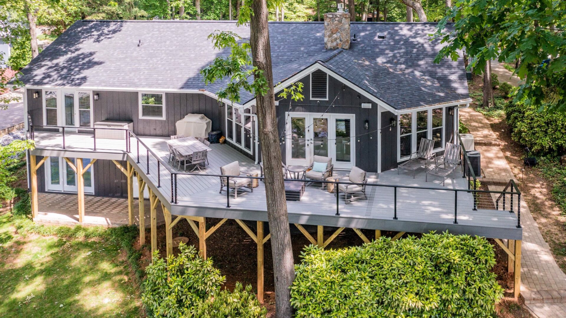 Modern elevated gray composite deck with black cable railing for lakefront outdoor living, custom built by Carolina Decks in the Charlotte, NC area.