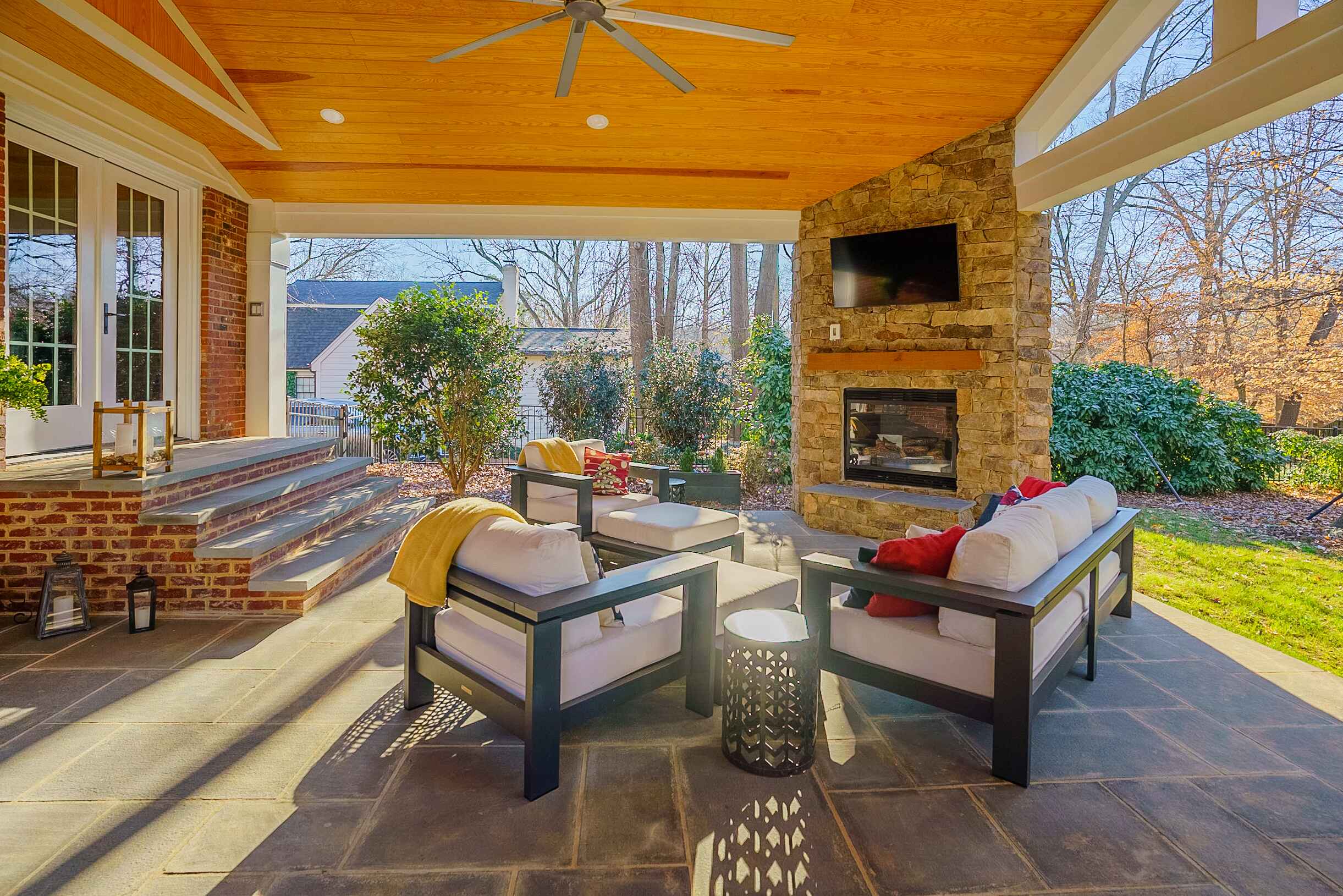 Covered patio with stone fireplace, bluestone floor, and wood ceiling, custom built by Carolina Decks in the Charlotte, NC area.