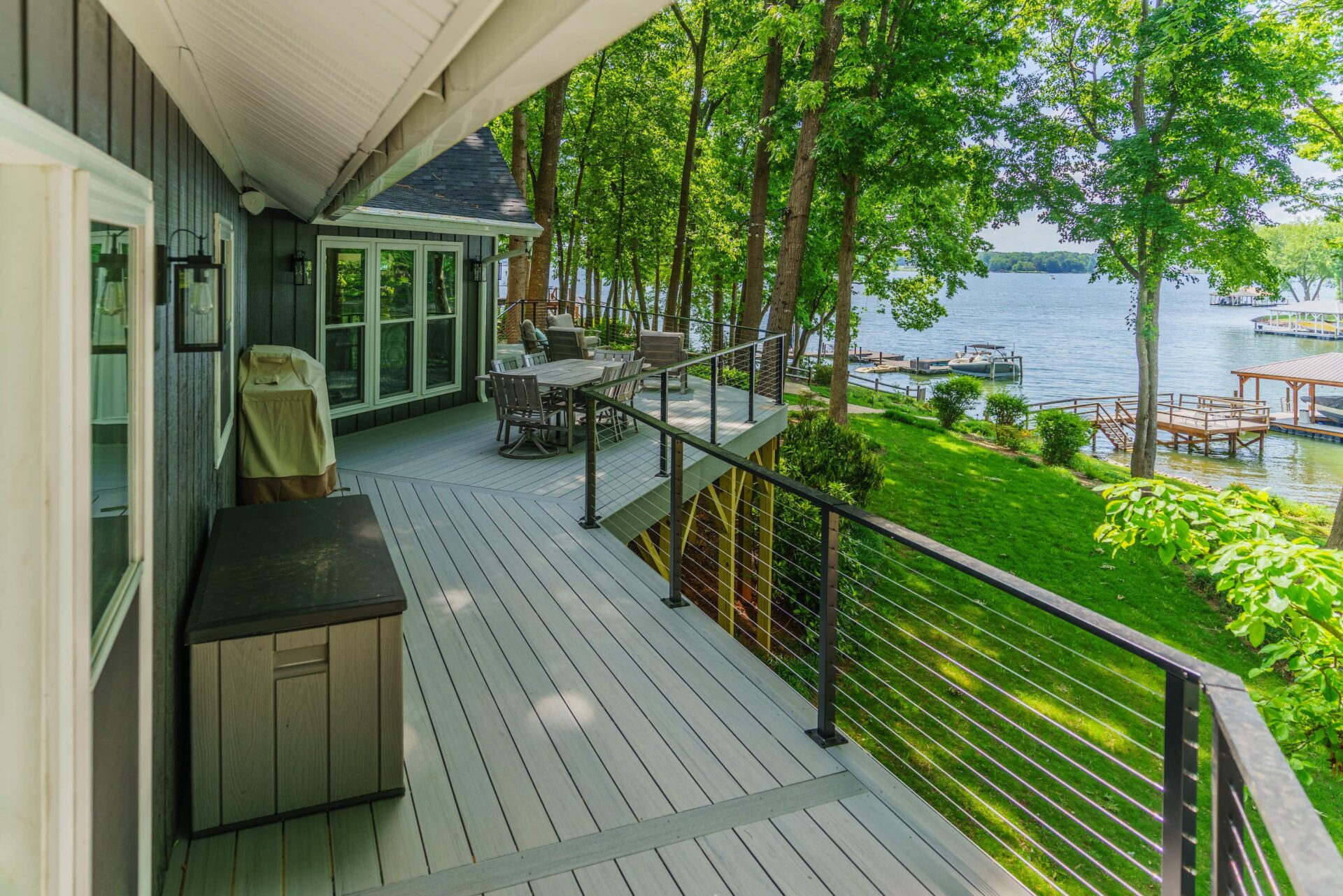 Spacious grey composite deck with modern black cable railing overlooking a serene lake, custom built by Carolina Decks in the Charlotte, NC area.