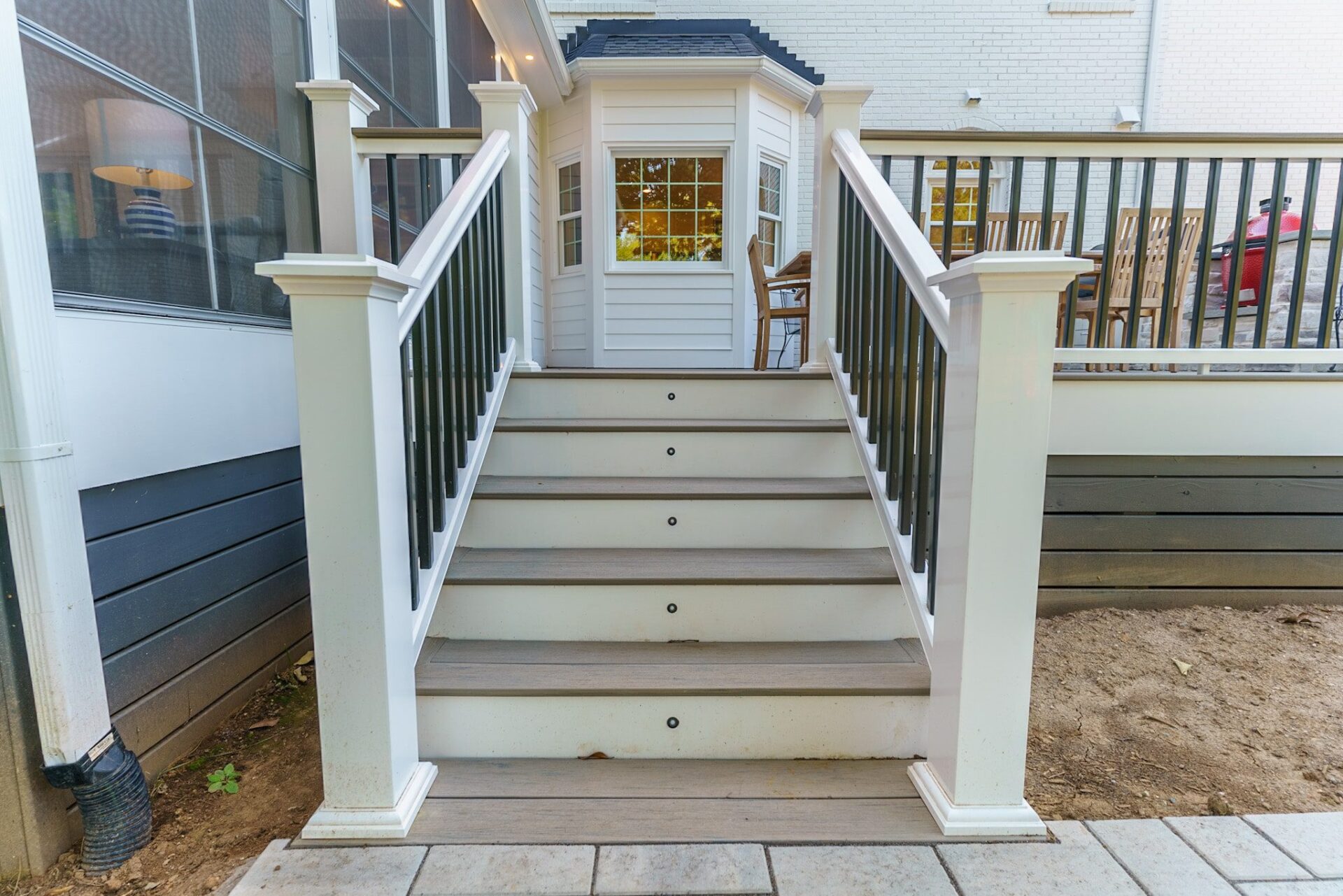 Composite deck stairs with integrated step lighting and two-tone railing, custom built by Carolina Decks in the Chadwyck Farms neighborhood.