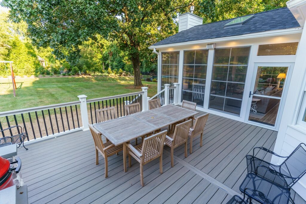 Spacious gray composite deck with white railings connects to a bright screened porch, custom built by Carolina Decks in the Chadwyck Farms neighborhood.
