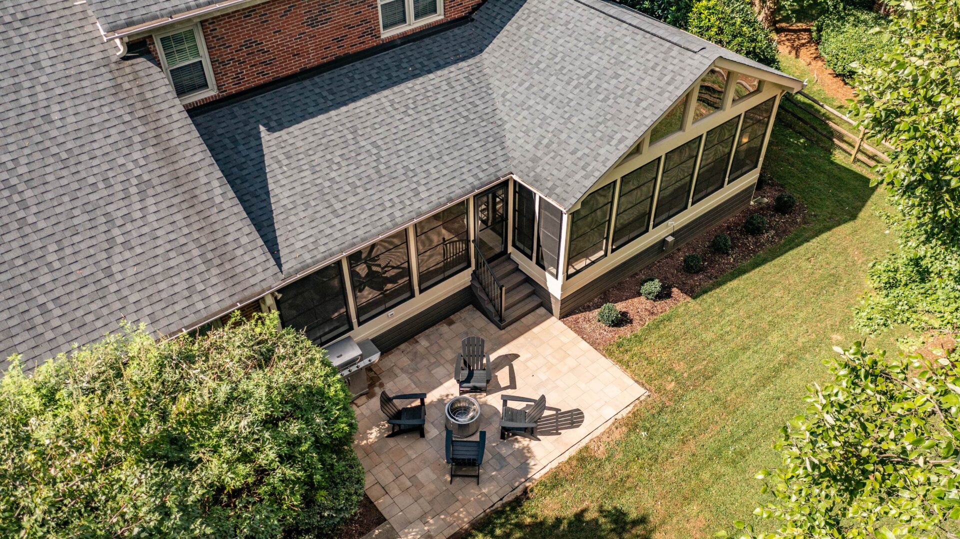 Gable screened porch leading to a paver patio with fire pit and seating, custom built by Carolina Decks in the Charlotte, NC area.