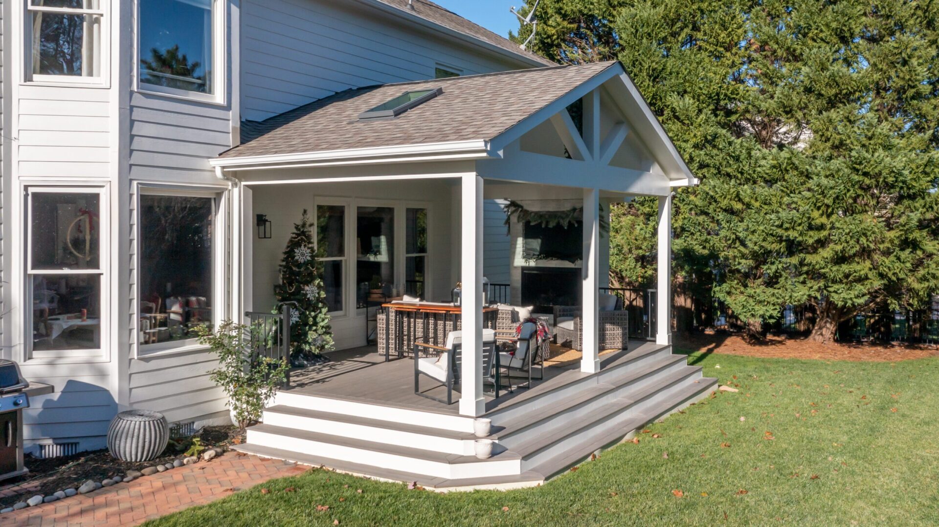 Covered composite deck with a gable roof, fireplace, and wide steps, custom built by Carolina Decks in the Mint Hill, NC area.