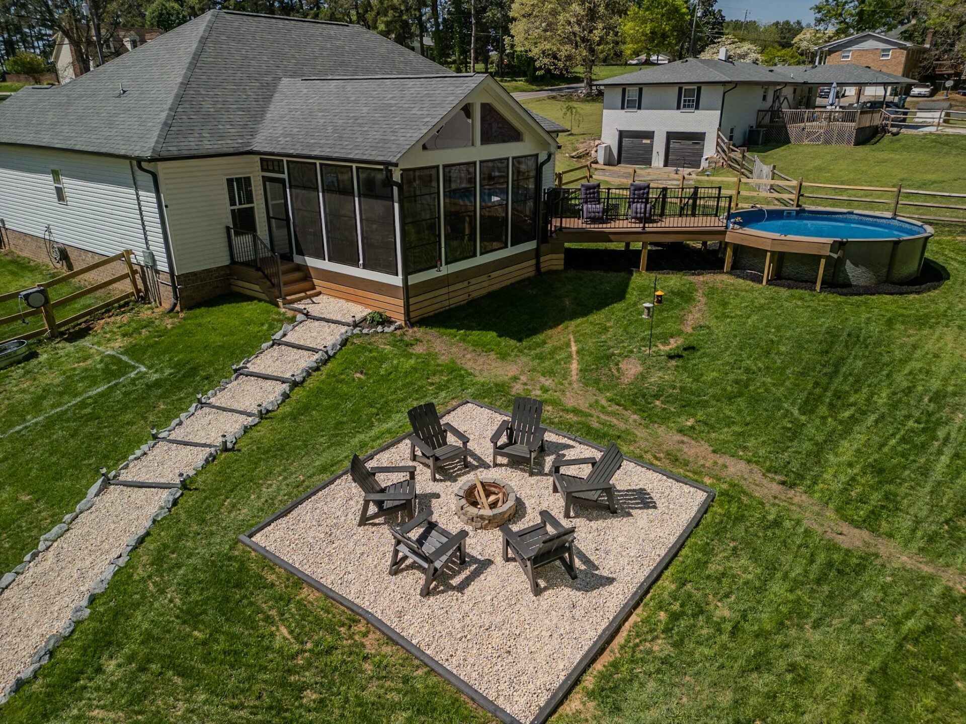 Expansive screened porch, multi-level wood deck with above-ground pool, and a gravel fire pit area, custom built by Carolina Decks in the Pineville, NC area.
