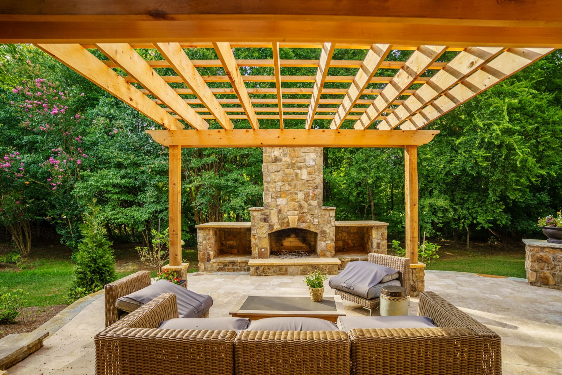 Elegant wood pergola shades a custom stone fireplace and spacious paver patio, custom built by Carolina Decks in the Weddington, NC area.