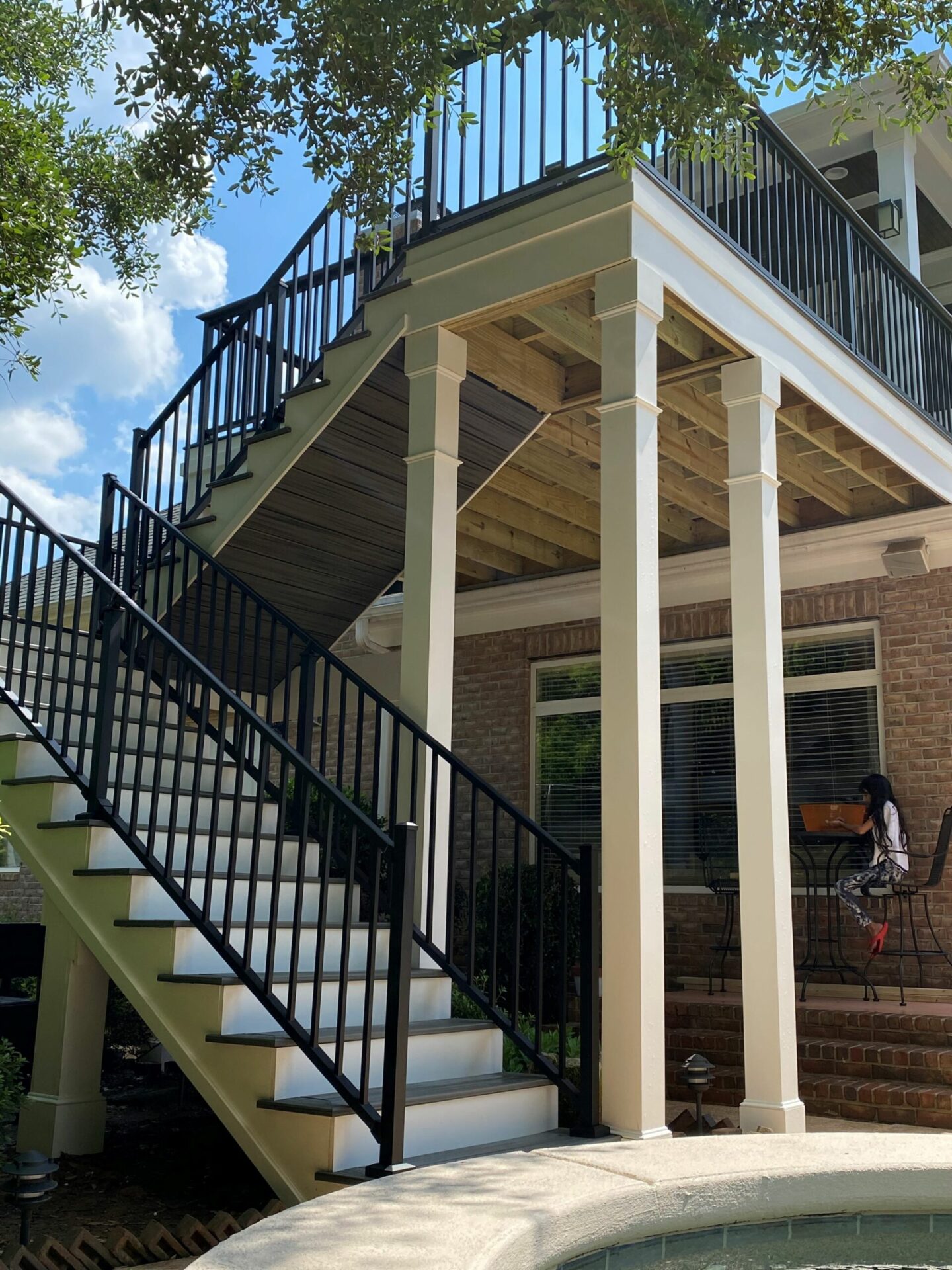 Modern black railing paired with a TimberTech Dark Hickory PVC deck installation for a luxury home backyard.