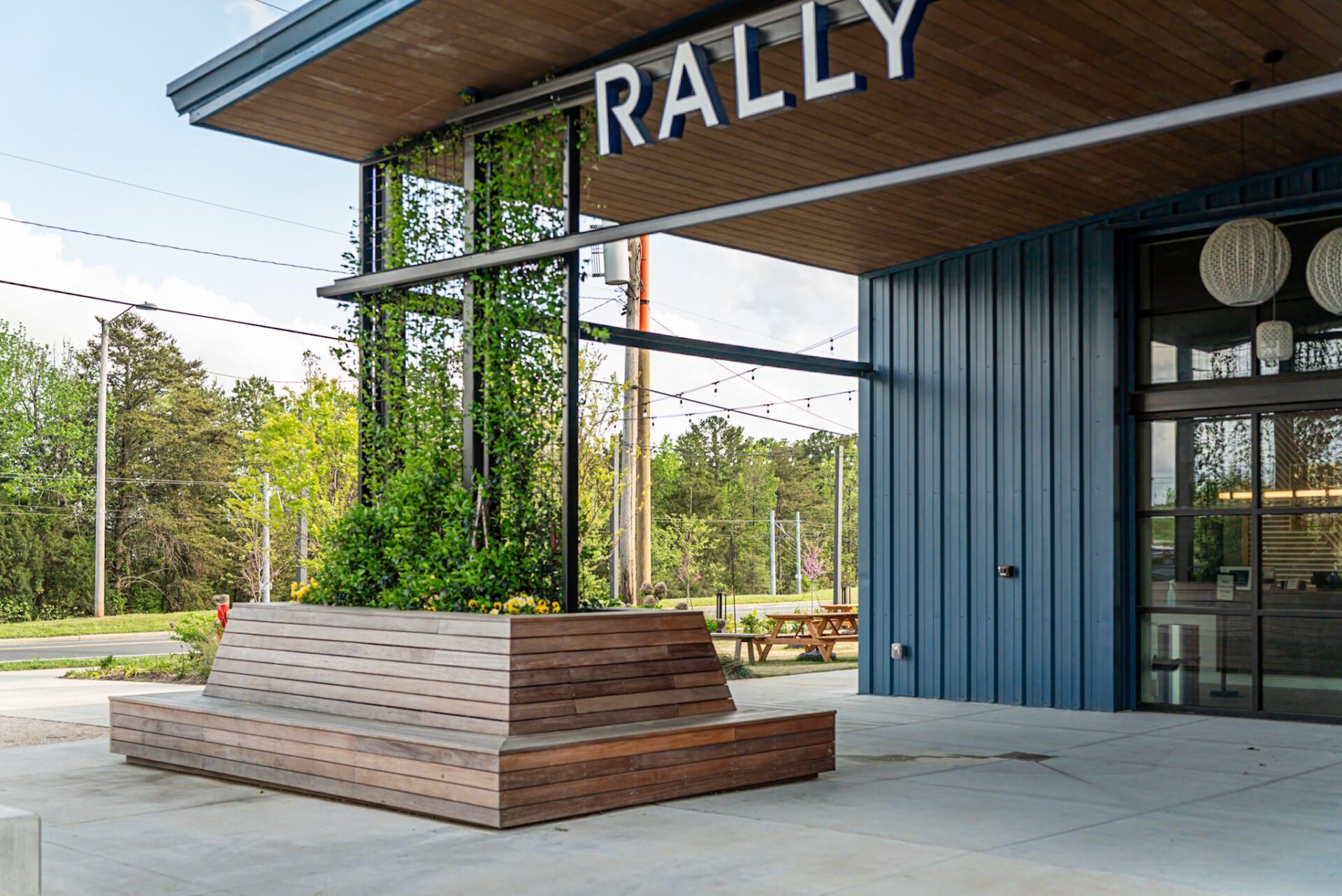 Slatted wood bench, planter with trellis, concrete patio, custom built by Carolina Decks at Rally Pickleball.