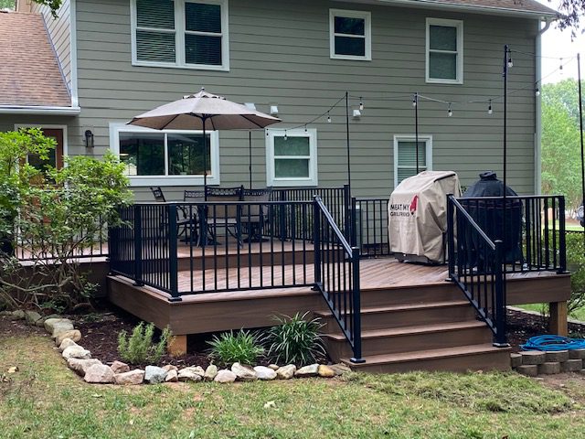 Brown composite deck with black railings, stairs, and outdoor lighting, custom built by Carolina Decks in the South Charlotte, NC area.