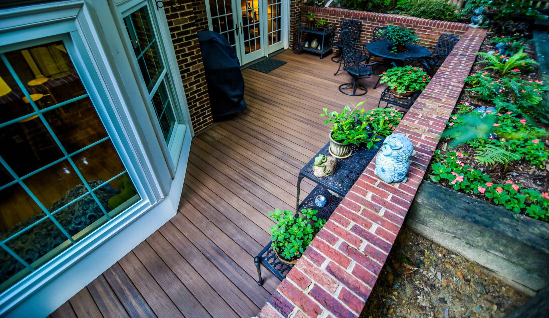 Spacious backyard composite deck bordered by a custom red brick retaining planter wall on a home in Benton Woods.