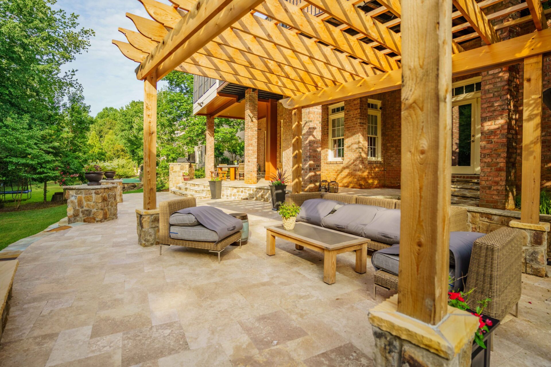 Natural stone patio featuring a custom cedar pergola and comfortable outdoor lounge seating.