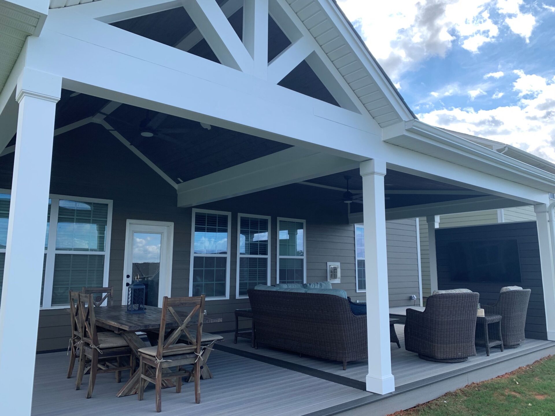 Exterior view of a large white open-air pavilion porch addition with a grand vaulted gable roof built over an extended backyard deck.