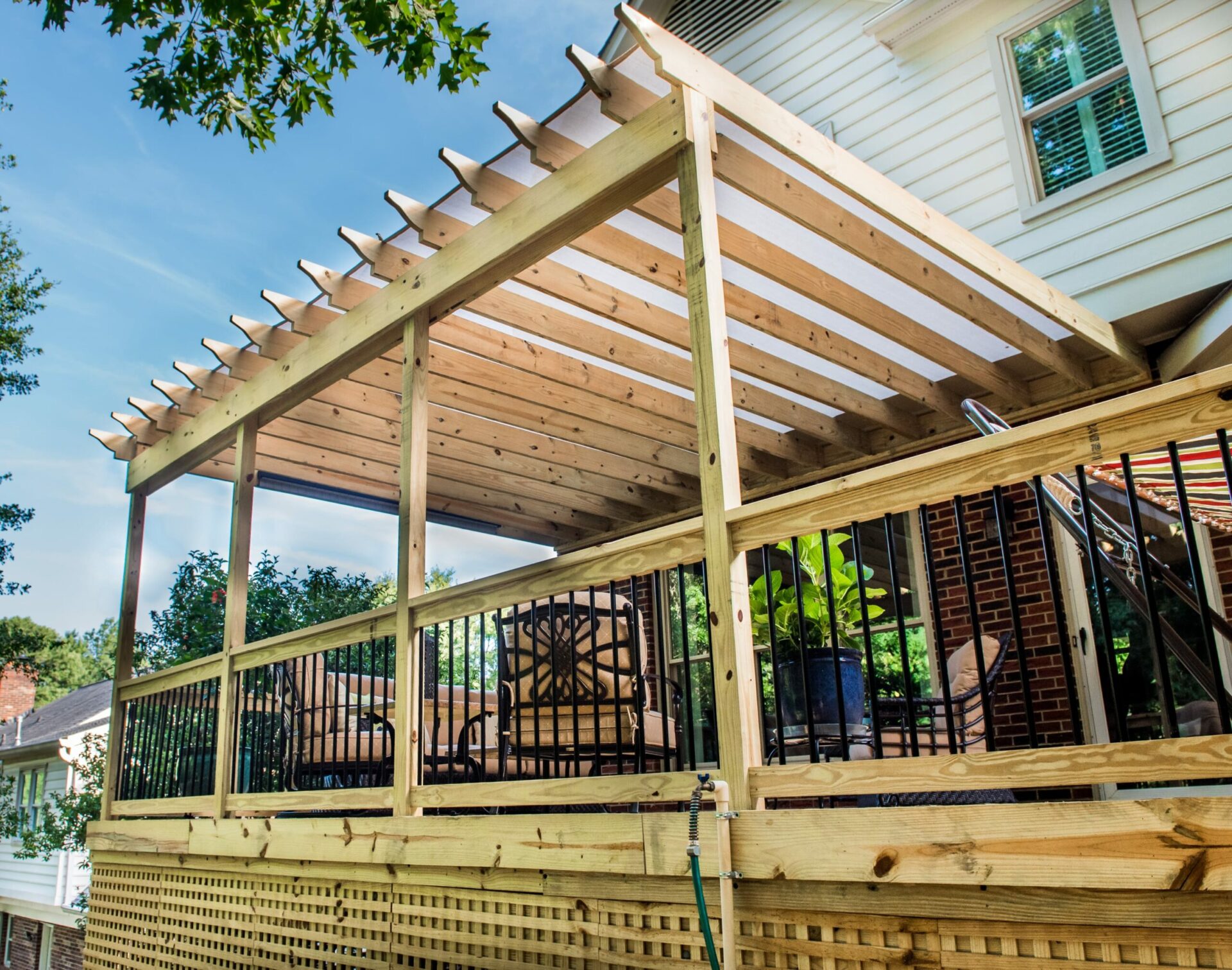 Detail shot of a wood pergola with clear polycarbonate roofing panels for rain protection.