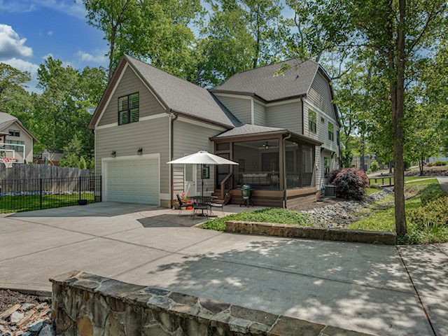 Exterior view of a new custom screened porch addition in Carmel Forest, South Charlotte, featuring white siding, a black-framed door, and a Belgard Cobblestone paver patio below.