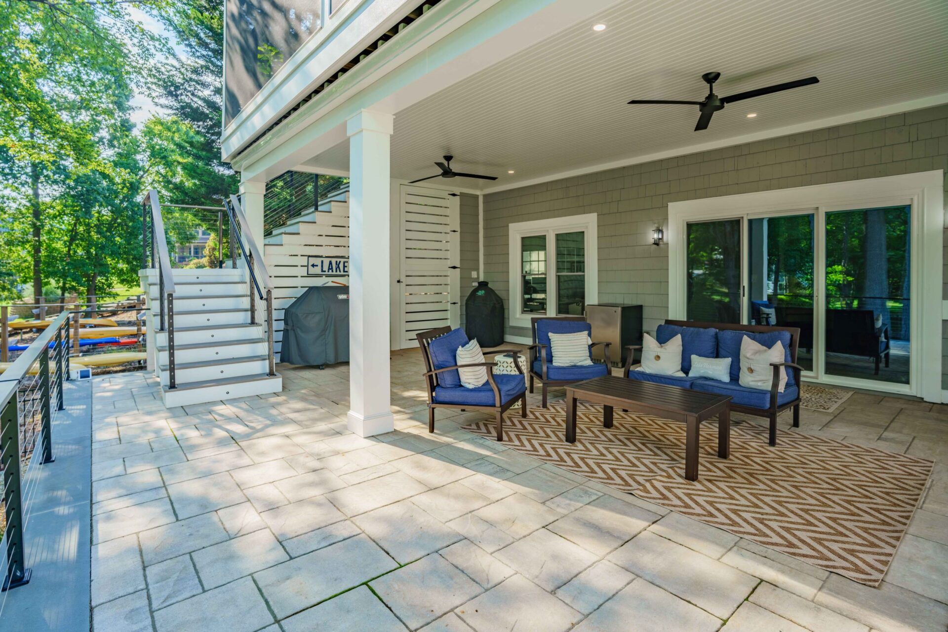 Spacious covered paver patio featuring beadboard ceiling, white columns, and cable railing stairs, custom built by Carolina Decks in the Southshore, NC area.
