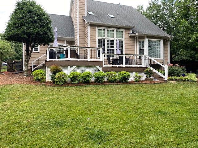 Wide view of a two-level composite deck built with TimberTech Dark Roast boards and white vinyl railings on a tan siding home in Ravencrest South.