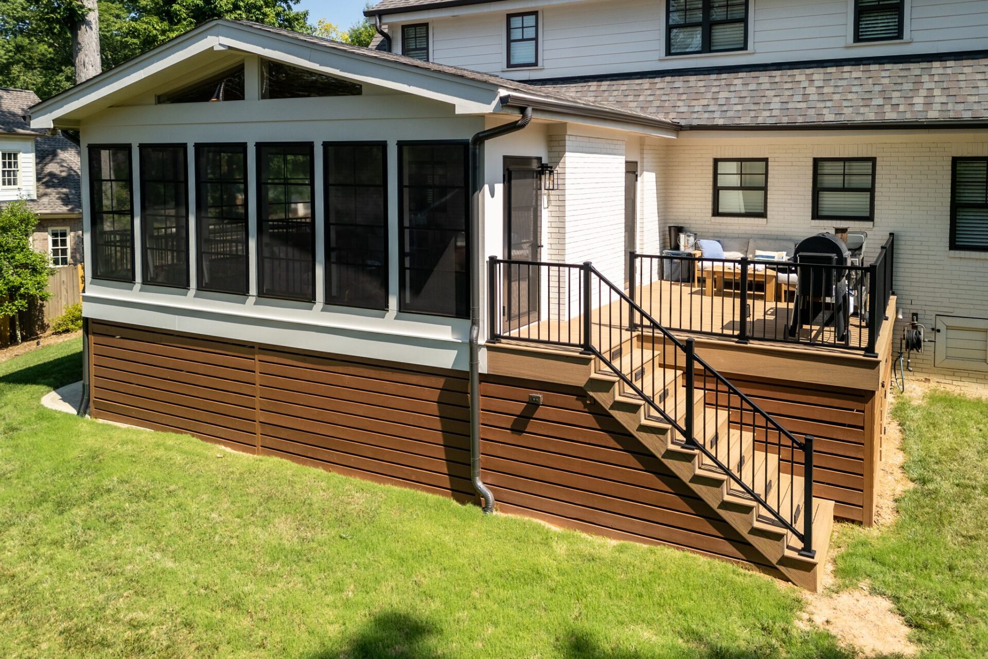 Spacious screened porch and multi-level composite deck with black railings and stairs, custom built by Carolina Decks in the Charlotte, NC area.
