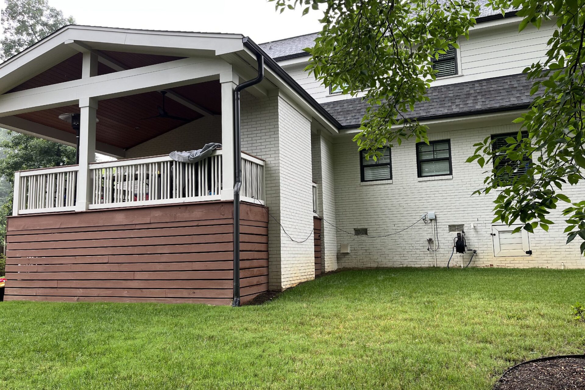 Old covered deck features white railings, wood ceiling, and brown plank skirting