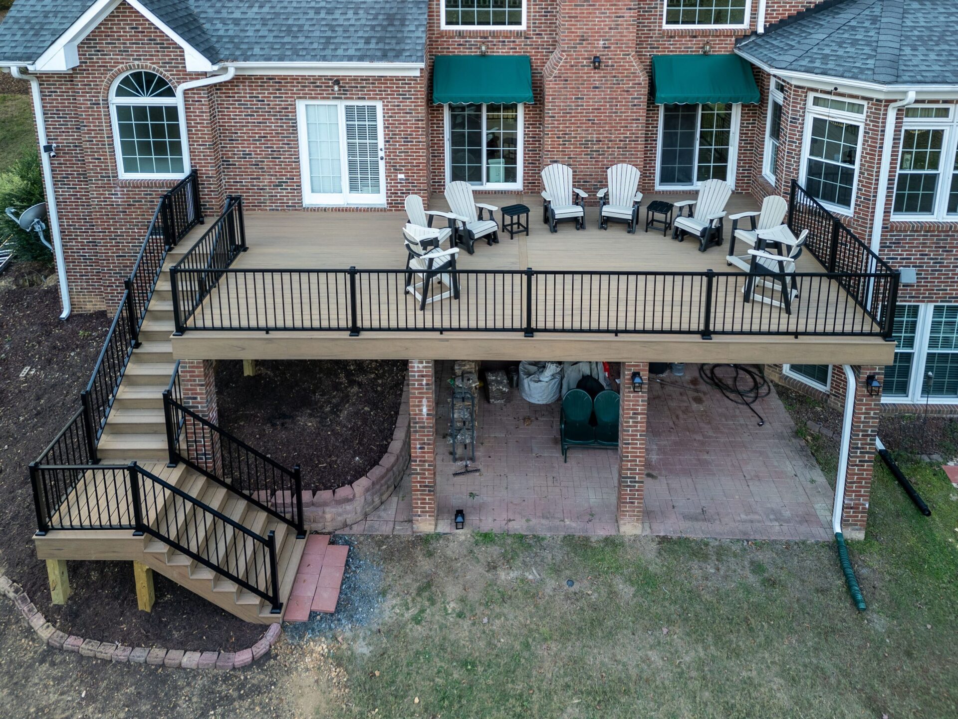 Elevated composite deck with black aluminum railings, matching stairs, and lower brick patio, custom built by Carolina Decks in the Charlotte, NC area.