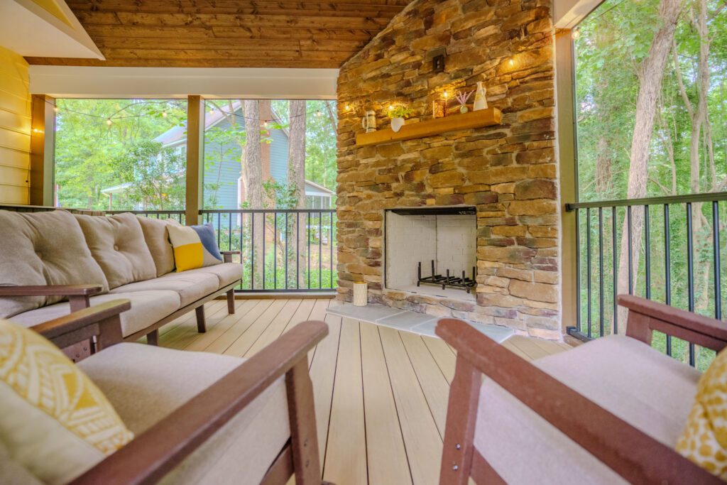 Covered porch with stone fireplace, wood ceiling, and composite deck custom built by Carolina Decks in the Charlotte, NC area.