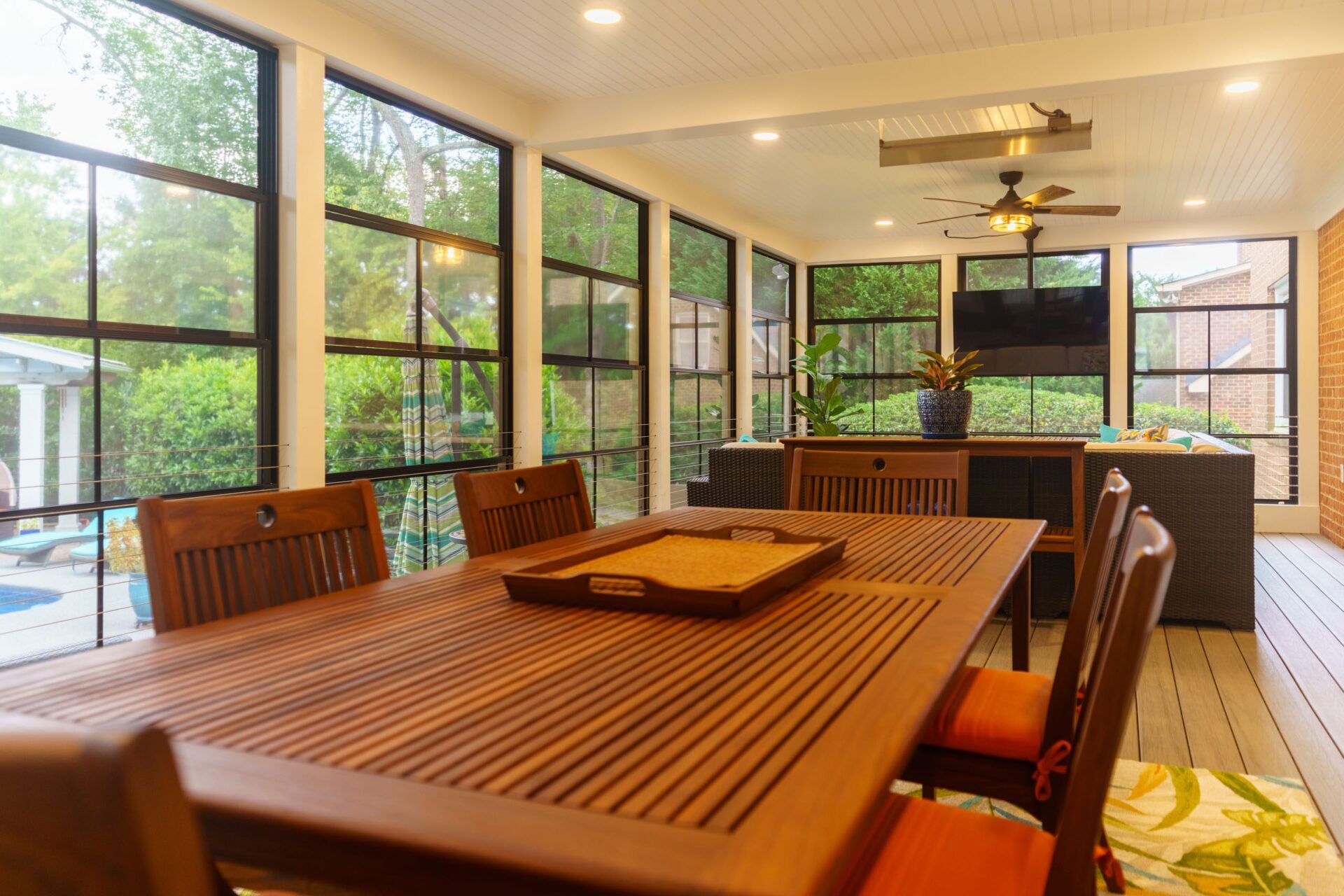 A spacious sunroom with black window walls, a beadboard ceiling, and composite decking, custom built by Carolina Decks in the Charlotte, NC area.