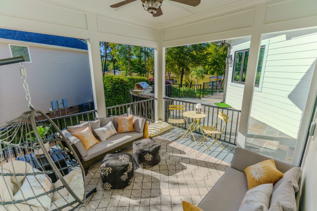 Elegant white covered porch and multi-level deck overlooking a lake with metal railings, custom built by Carolina Decks in the Charlotte, NC area.