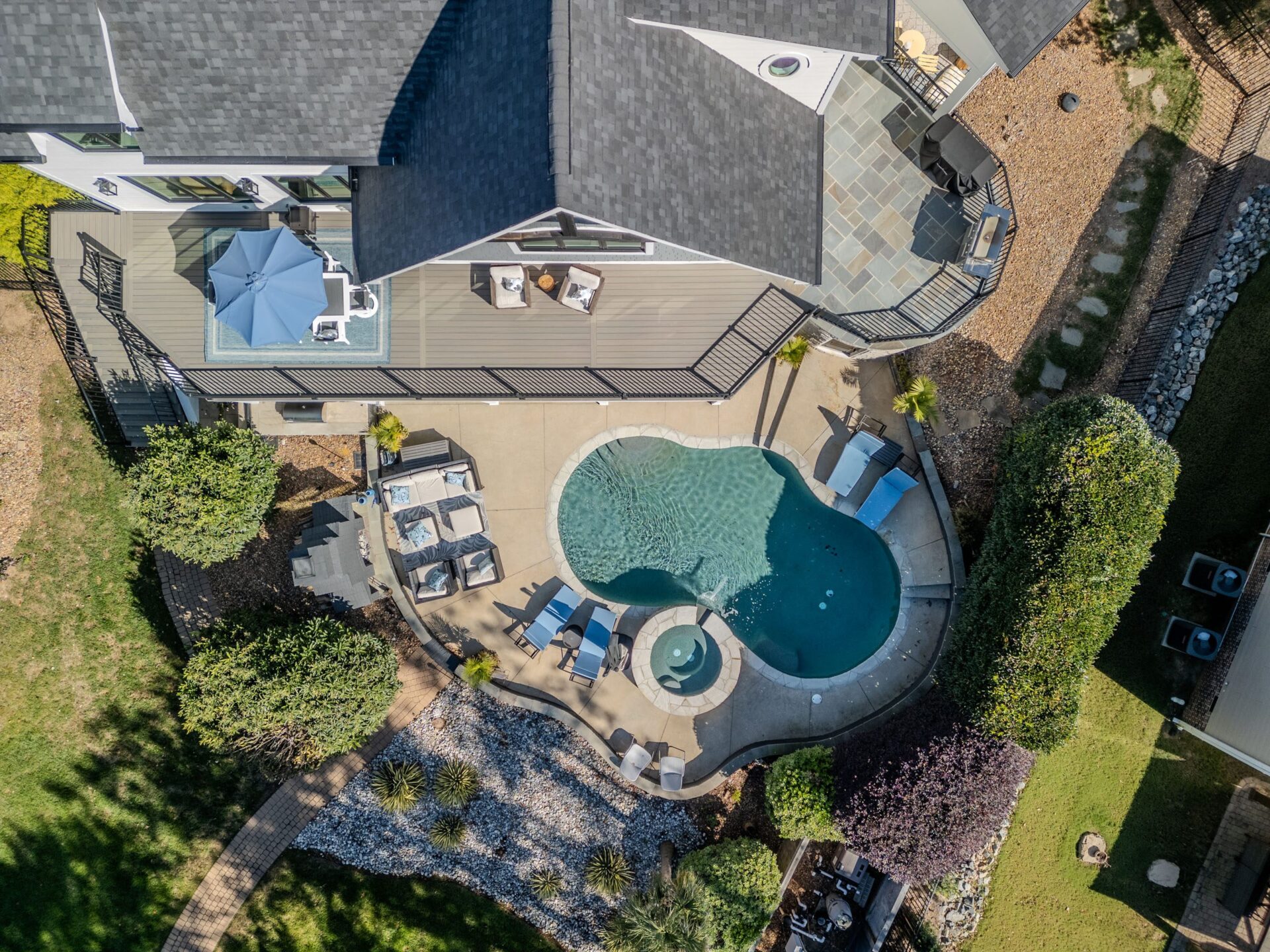 Multi-level composite deck, stone patio, and pool area with black railings, custom built by Carolina Decks in Providence Country Club area.