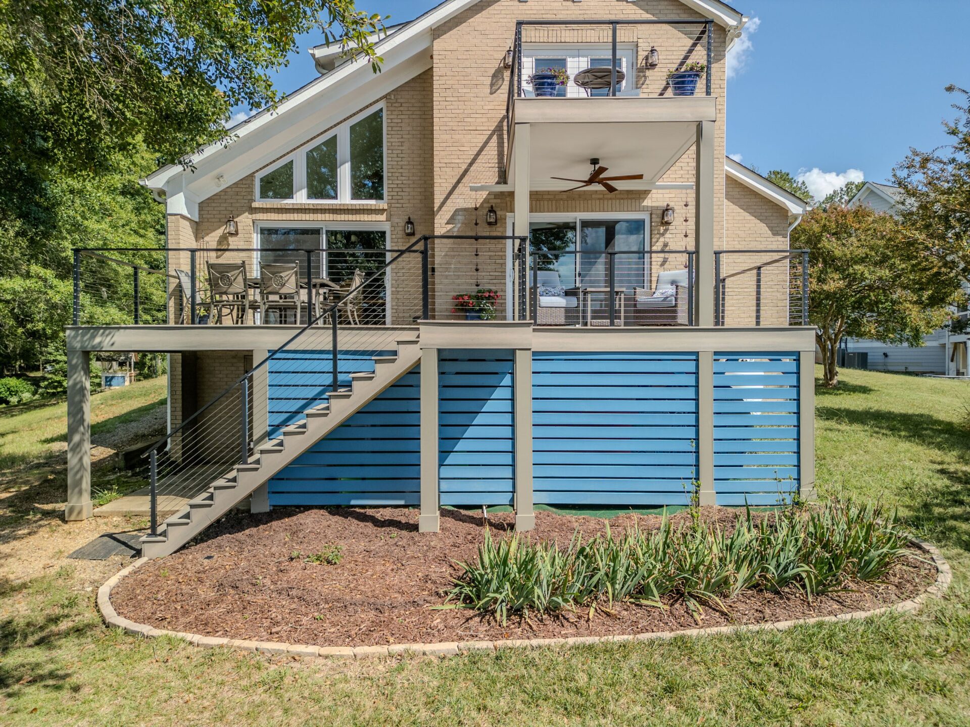Multi-level composite deck with modern cable railing and vibrant blue skirting, custom built by Carolina Decks in the Charlotte, NC area.