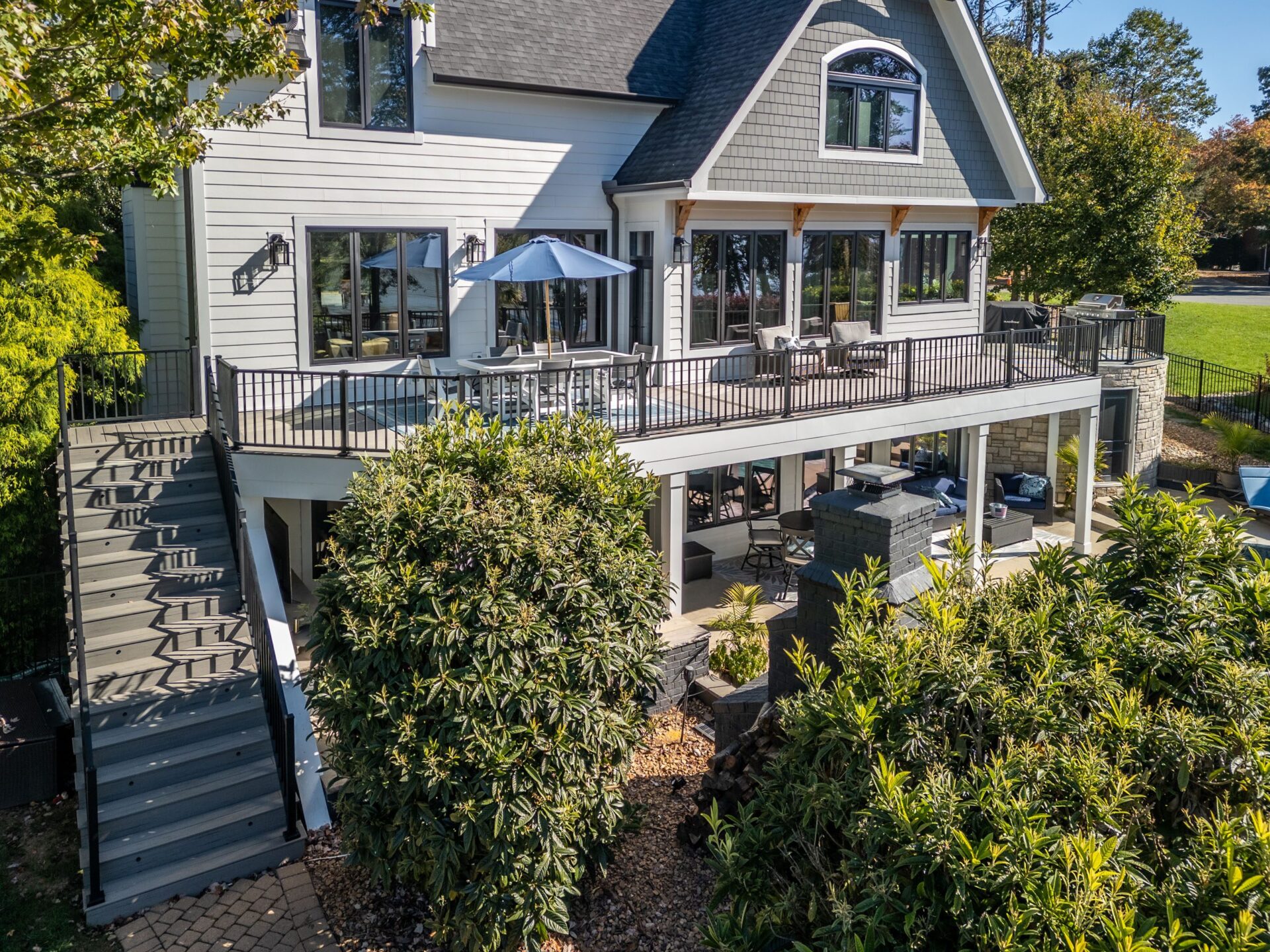 Expansive multi-level gray composite deck with black railings and lower patio area, custom built by Carolina Decks in Lake Norman.