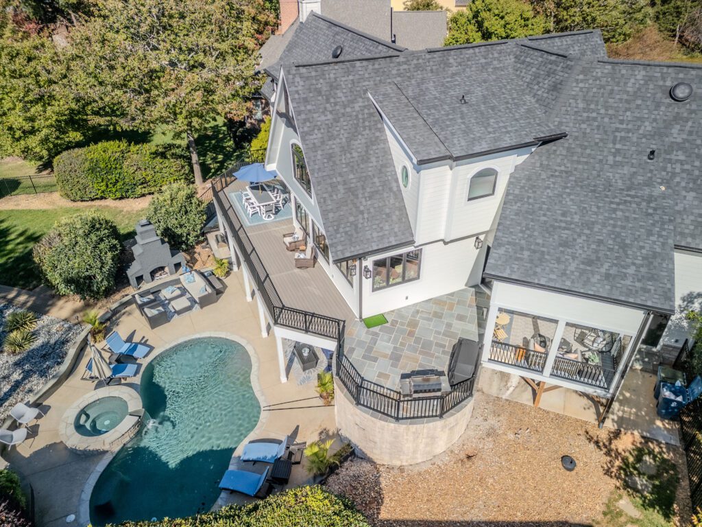 Multi-level composite deck, bluestone paver patio, and pool area with black railings custom built by Carolina Decks in the Lake Norman area.