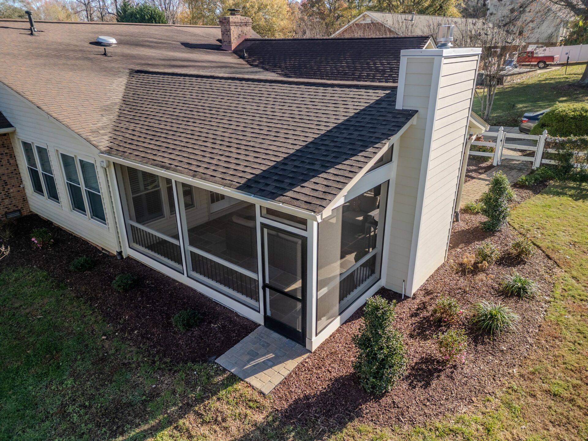 Newly built screened porch addition features a gable roof, light siding, and a paver walkway, custom built by Carolina Decks in the Kings Mountain area.