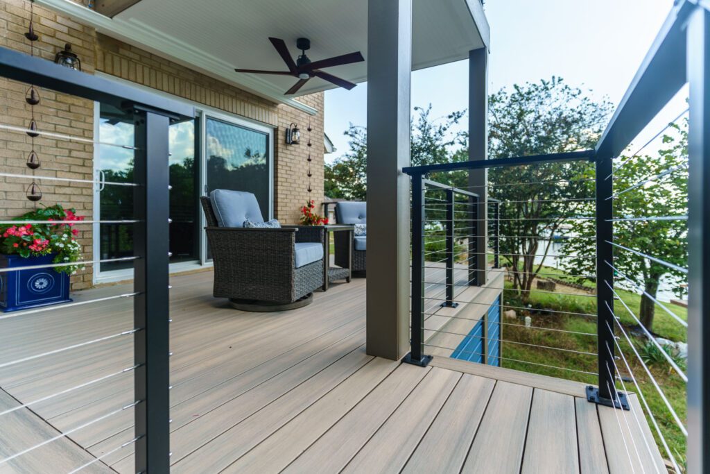 Light composite deck with modern black cable railing and covered space, custom built by Carolina Decks in Tega Cay.