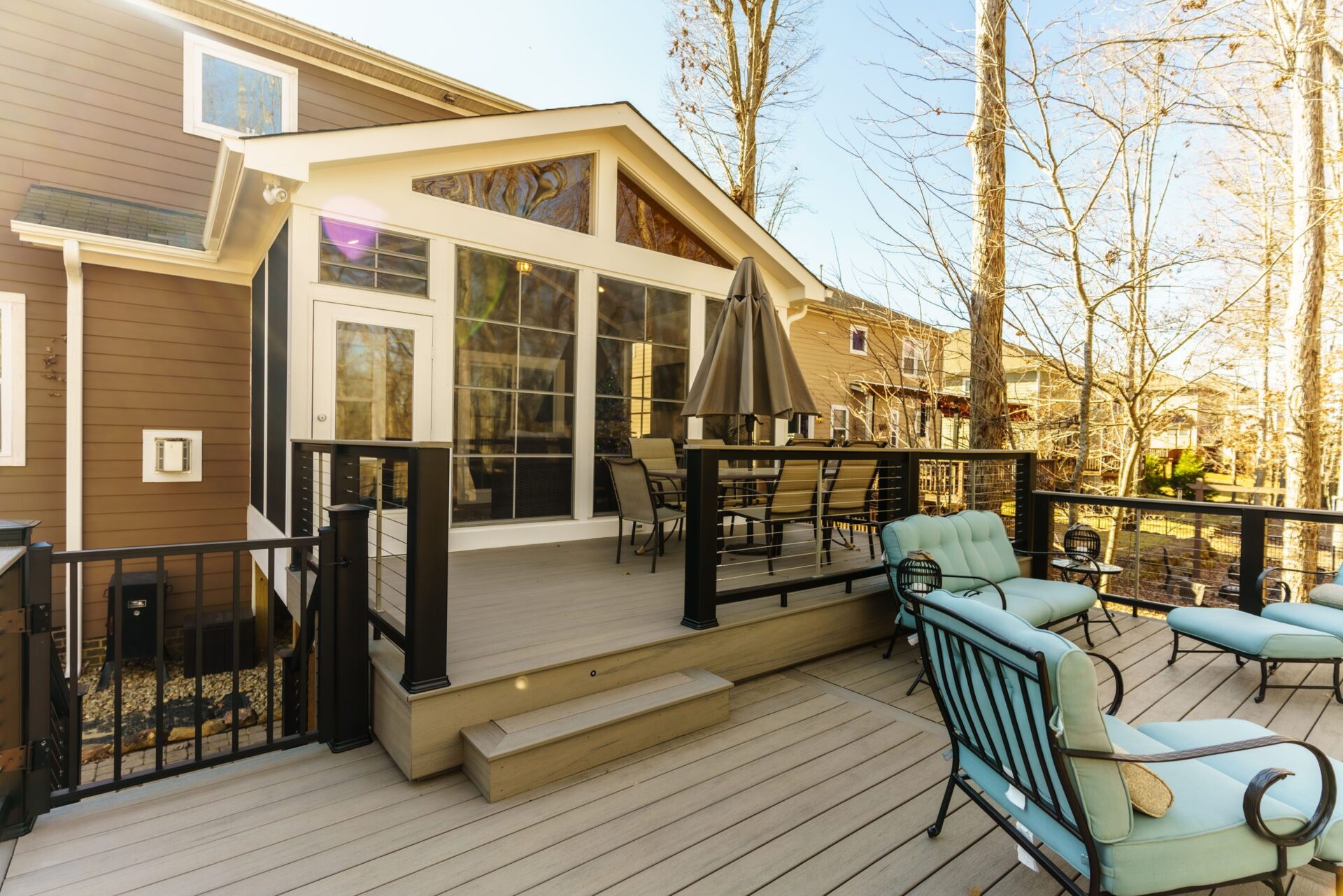 Light grey composite deck with black cable railings and a bright gable screened porch, custom built by Carolina Decks in the Charlotte, NC area.