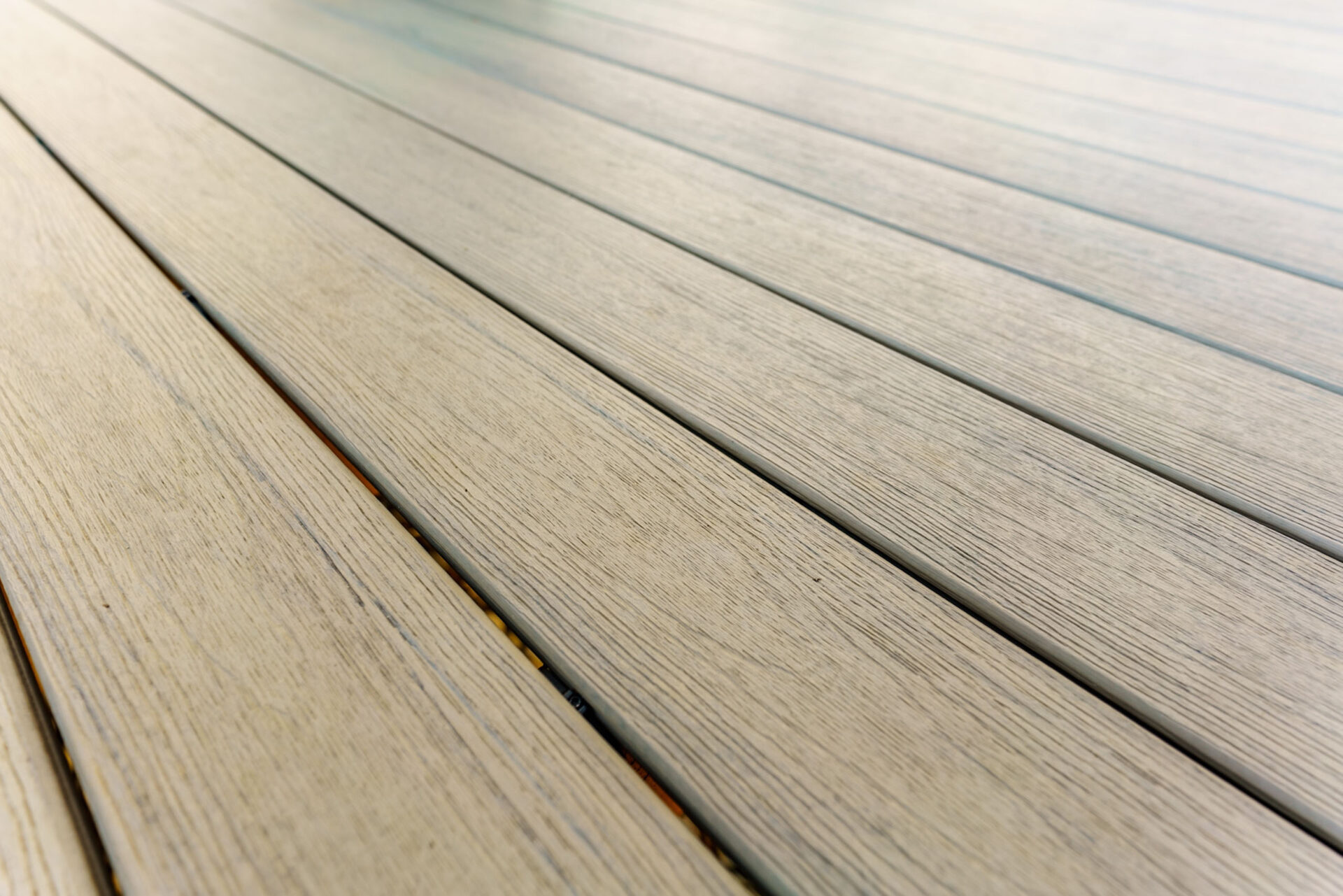 Close-up of modern light-colored composite deck boards with a realistic wood grain texture, custom built by Carolina Decks in the Waxhaw area.