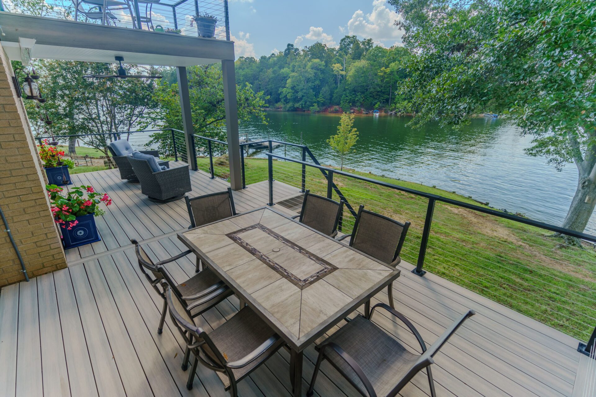 Spacious multi-level composite deck with black cable railing overlooks a lake, custom built by Carolina Decks in the Charlotte, NC area.
