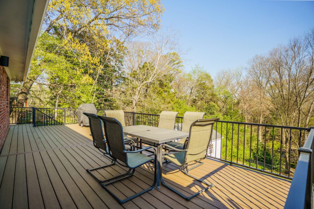 An outdoor dining table and chairs set on a new elevated composite deck built with TimberTech Dark Roast decking and black Trex aluminum railings in Charlotte's Stonehaven neighborhood.