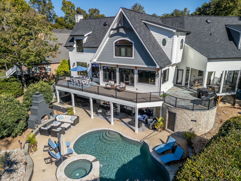 Luxurious multi-level deck, paver patio, swimming pool, and outdoor fireplace with custom stone accents, custom built by Carolina Decks in the Lake Norman, NC area.