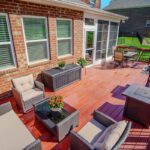 A vibrant red-stained wood deck seamlessly connects to a bright screened porch, perfect for outdoor living, custom built by Carolina Decks in the Deerbridge neighborhood.