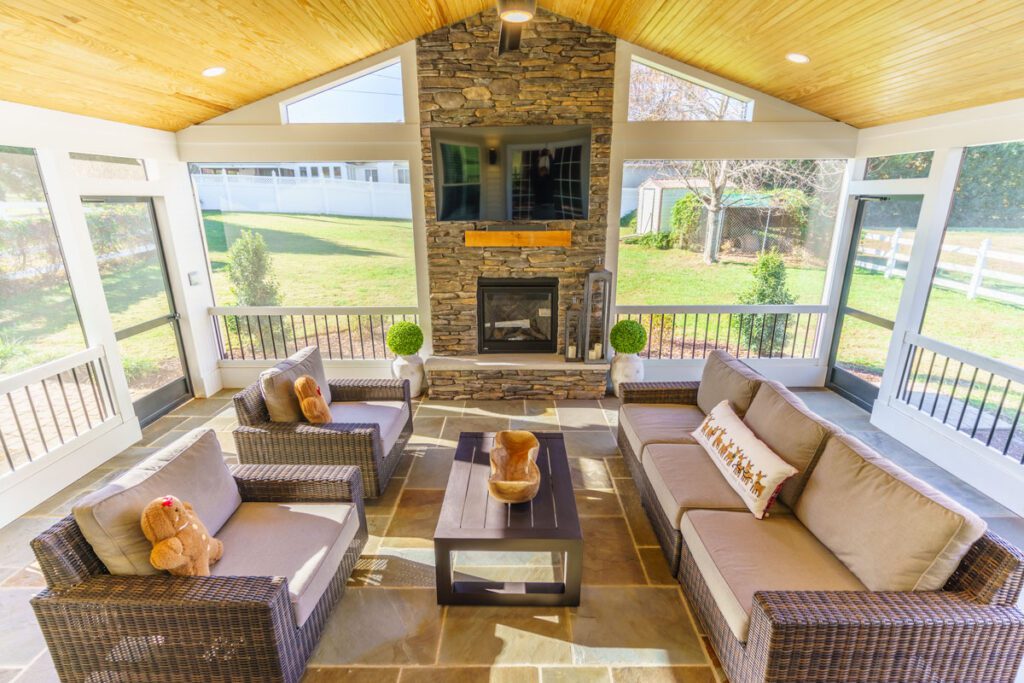A screened porch with vaulted wood ceiling, stone fireplace, and flagstone floor, custom built by Carolina Decks in the Kings Mountain, NC area.